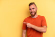 © Asier - Young caucasian man isolated on yellow background smiling and pointing aside, showing something at blank space.
