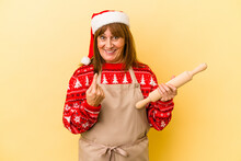 Middle Age Caucasian Woman Cooking Cookies For Christmas Isolated On Yellow Background Pointing With Finger At You As If Inviting Come Closer.