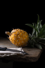 Wall Mural - pineapple, tropical fruit on a table top, with a knife in front, dark background with copy space