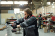 © pressmaster - Young worker of industrial plant using electric drill while working with metallic sheet which is part of huge detail or machine