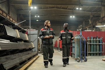 Poster - Young confident African American engineer talking to his colleague on the move about quality of new equipment for industrial machinery