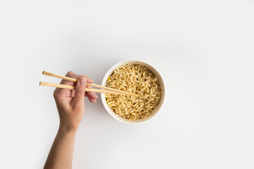 Chinese noodles in a paper mask with wooden chopsticks on a white background. Top view, fly lay