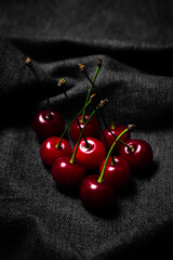 Sticker - Red cherry on black fabric. Food photo in low key. sweet fruit