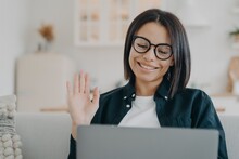 Entrepreneur Girl In Glasses Has Video Call On Computer And Waving Hand. Distance Work At Home.