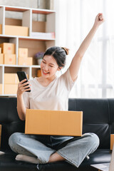 Portrait of a small business startup, SME owner, female entrepreneur Excited about the sales that exceeded the target. check work order online To prepare to pack boxes for sale to SME customers online