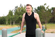 © Евгений Шемякин - Young handsome fit athletic strong man is training doing triceps and chest pull ups in park on sports ground outdoors on bar at summer. Open air gym. Bodybuilding, fitness sport healthy lifestyle.