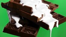 Close Up Of Chocolate Bars With Draining White Glaze Isolated On Chroma Key Green Wall Background. Stock Clip. Black Chocolate And White Glaze.