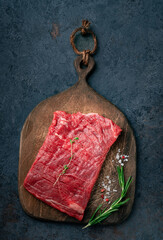 Wall Mural - Raw flank steak or Outside skirt steak on a wooden board with grilling seasonings, close up, top view