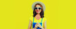 Summer portrait of happy smiling young woman with lollipop wearing straw hat on yellow background