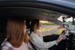© deine_liebe - Two young women laughing in the car during a summer road trip. Best friends have fun together as they drive through the countryside. A happy couple of girls relaxing on a road trip.