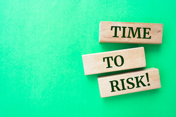 Time to risk words on wooden blocks on green background.