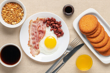 Wall Mural - Hearty homemade family breakfast. Eggs, bacon, sausages, beans, croissants, toast and coffee on the table. Top View