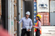 © nikomsolftwaer - Business Logistics concept, Foreman control loading Containers box of cargo freight ship for Logistic planning. Industrial worker works with co-worker at overseas shipping container yard .