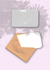 Wall Mural - An envelope with two sheets of textured white paper on the pink background of the table. Mockup overlay with the plant shadows. Natural light casts shadows from a Rowan branch