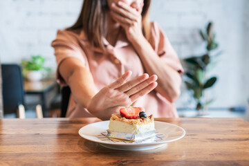 Asian teenager girl refuses to eat cheese cake. Say NO to unhealthy food, healthy eating and lose weight concept