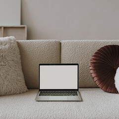 Wall Mural - laptop computer with blank screen on comfortable beige sofa with pillows. aesthetic influencer style