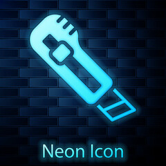 Sticker - Glowing neon Stationery knife icon isolated on brick wall background. Office paper cutter. Vector