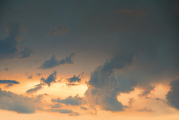 Wall Mural - dark slate blue sky with floating clouds and yellow light after thunderstorm