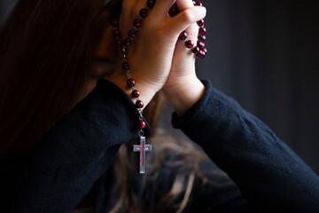 Christianity theme – prayer.  Christian woman with Bible praying with hands crossed keeping rosary.