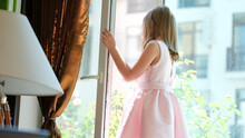 Small Child Standing On Windowsill At Open Window