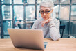 © oatawa - Modern mature middle aged business woman using laptop working and web surfing on desk.