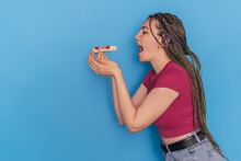 The Girl Pulls A Piece Of Cherry Pie To Her Mouth Against A Blue Background.
