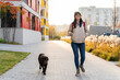 © NFstock - Caucasian gorgeous woman looking away while walking with her dog through the street and enjoying a good sunny weather. Walking and taking care of the pet concept