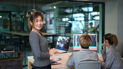 software engineers team leader standing with laptop and smiling to camera. developing programming an