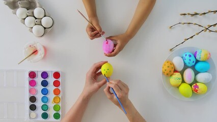 Wall Mural - easter, holidays and people concept - hands of child and parent coloring eggs on white backhround, top view