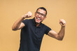 © denis_vermenko - Cheerful handsome African american black man making yes gesture while excited about winning. Ecstatic young fan rooting and expressing support. Success concept isolated over beige background.