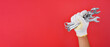 © dera - hand wearing white gloves holding combination wrench and box end wrench isolated red background