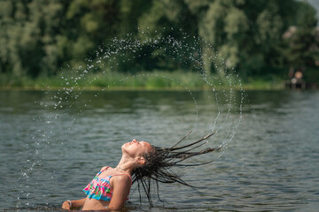 Wall Mural - A little girl splashes in a pond during the day.