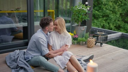 Wall Mural - Young couple in love cuddling and kissing outdoors on terrace, weekend away in tiny house in countryside, sustainable living.