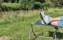 Woman With Sportshoes On A Bench Outdoor In The Grass