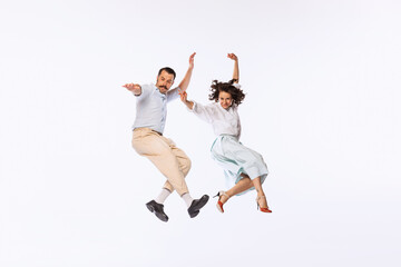 Wall Mural - Portrait of young beautiful couple, man and woman, dancing, jumping isolated over white studio background