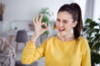 Photo of crazy nice charismatic positive lovely lady show okey signs wink wear yellow pullover comfortable home indoors