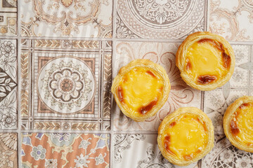 Wall Mural - Traditional portuguese vanilla pudding puff pastry pastel de nata on pink tiles background - top view, copy space