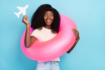 Wall Mural - Photo of overjoyed positive girl wear inflatable ring hold small paper airplane isolated on blue color background