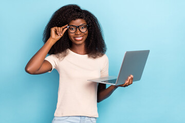 Sticker - Photo of cheerful smart lady hand touch glasses hold wireless netbook isolated on blue color background