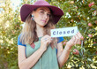 © Jade M/peopleimages.com - Portrait of one woman holding closed sign to advertise the end of apple picking season on orchard farm. Farmer closing agriculture business due to bankruptcy, recession, pandemic and failed economy