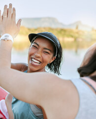 A cheerful woman is positive and motivating while out kayaking and enjoying water activity on a lake with her partner. Close up of two active friends giving high five while celebrating outdoors.