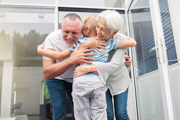 Poster - Senior grandparents hugging their small grandson at home. Little boy bonding and embracing smiling grandmother and grandfather. Adopted child feeling happy and grateful while hugging elderly couple