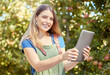 © Jade M/peopleimages.com - A female apple farmer standing and using a digital tablet while checking her plants. Smiling woman using technology to prepare for harvest on her farm. Monitoring plant growth and agriculture