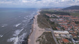 Fototapeta  - Aerial view of the Northern Littoral Natural Park in Esposende, Portugal. Sea, beach boulders, pebble shore, and waves. Sea waves breaking on rocks. Sunny beach with sand dunes and a cloudy sky.