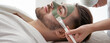 © New Africa - Cosmetologist applying mask on client's face in spa salon. Banner design