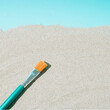 Minimal art creative concept of a paintbrush on the sandy beach and blue background. summer concept with copy space. flat lay view.