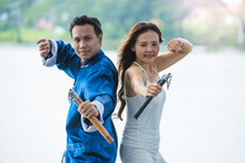 A Couple Of Young Man And Woman Practicing Kung Fu Or Martial Art With Nunchaku For Fighting Competition In The Park.