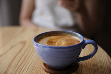 Wall Mural - Cappuccino coffee on wood and blur sitting female background