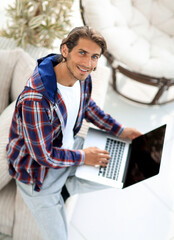 Wall Mural - young man working on laptop and looking at camera. view from above