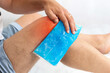 Man using cool gel pack on a swollen injured knee with Color Enhanced skin with red spot indicating location of the pain isolated on white. Medical and health care concept photo.